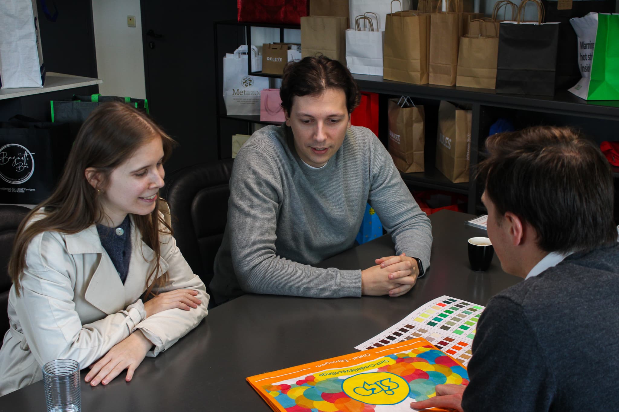 Klantgesprek in de showroom van TM pack met papieren draagtassen op de achtergrond en kleurstalen op tafel