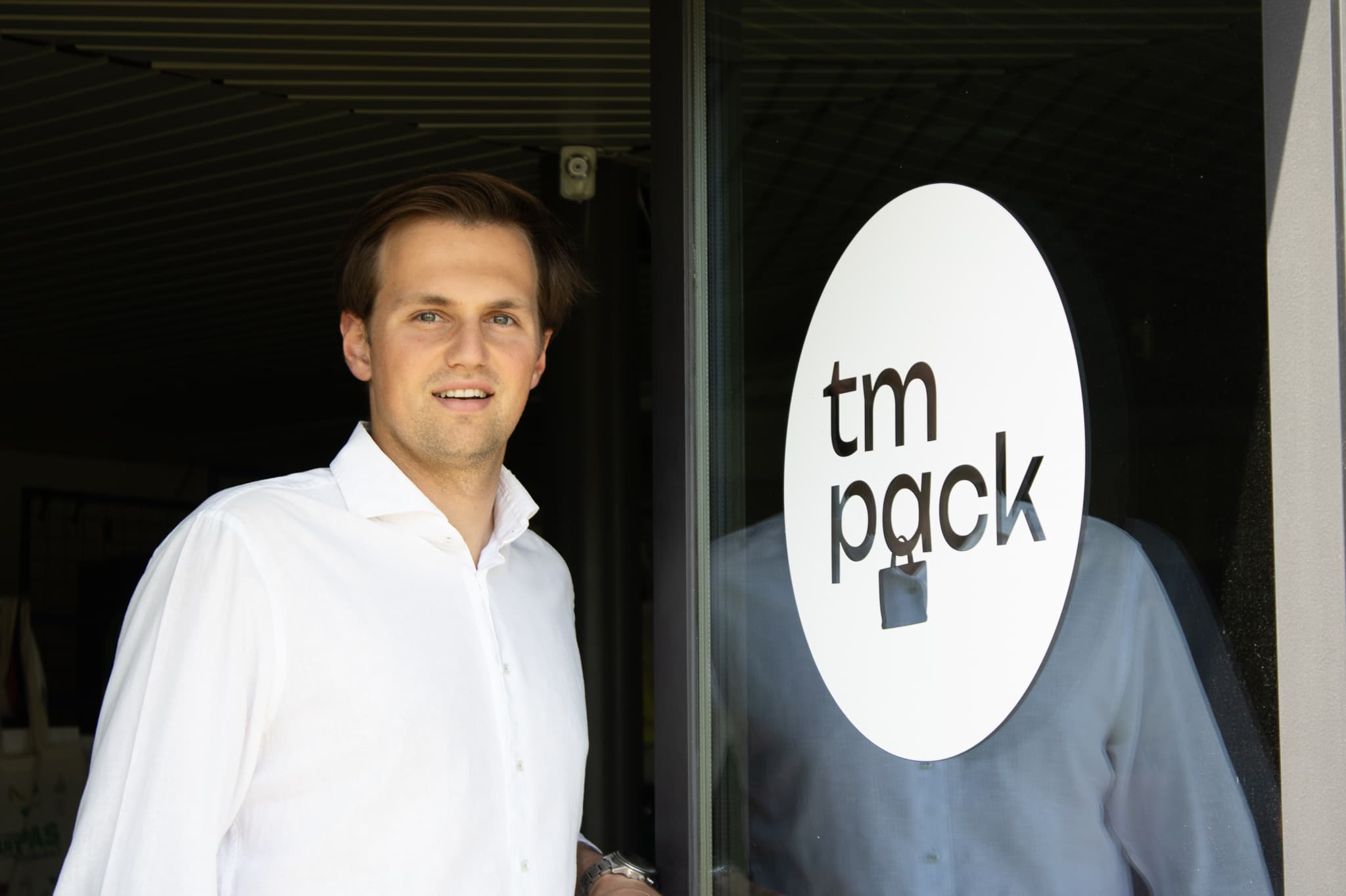 Thibault Vinckier opent de deur van de TM Pack-showroom in witte hemd